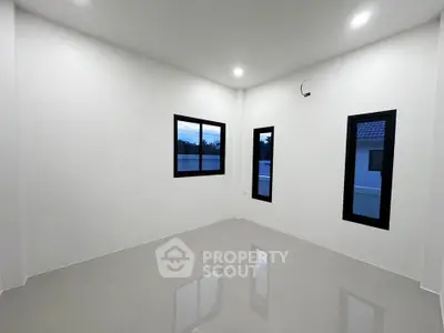 Spacious empty room with glossy floors and large windows, perfect for customization.