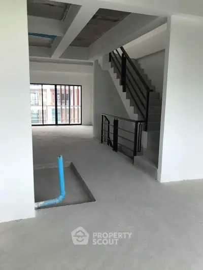 Spacious unfinished interior with staircase and large windows in modern building