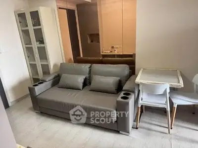 Modern living room with sleek gray sofa and dining area in stylish apartment.