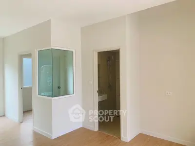 Spacious modern interior with light wood flooring and neutral walls, featuring a small bathroom and utility area.