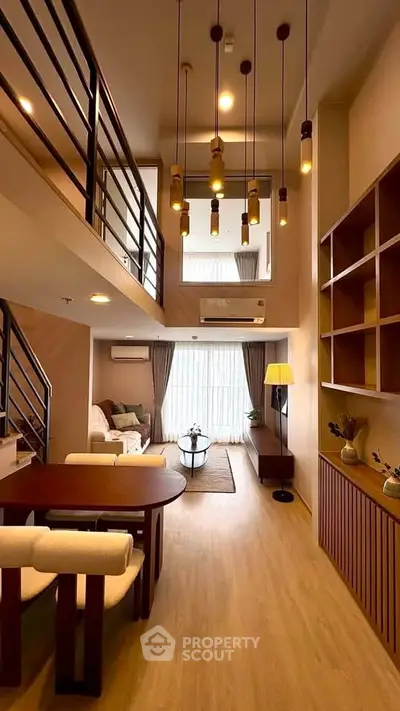 Modern duplex living room with high ceiling and stylish lighting, featuring cozy seating and elegant decor.