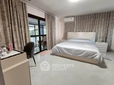 Spacious bedroom with elegant decor and large windows for natural light.