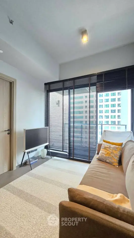 Modern living room with large windows and stylish decor in a high-rise apartment.