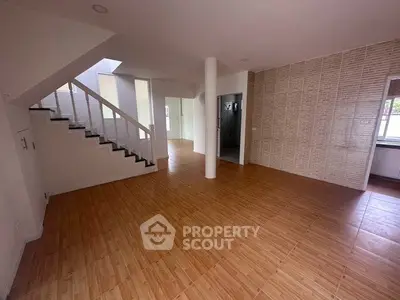 Spacious open-plan living area with wooden flooring and modern staircase.