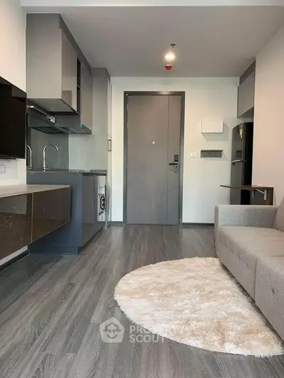 Modern living room with sleek kitchen, cozy sofa, and stylish flooring in a contemporary apartment.