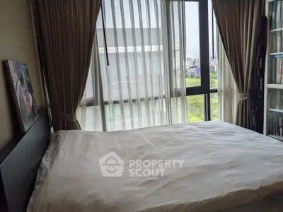 Cozy bedroom with large window and bookshelf, offering a serene view and natural light.