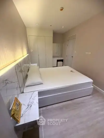 Modern bedroom with sleek design and marble accents, featuring a comfortable bed and ample storage space.
