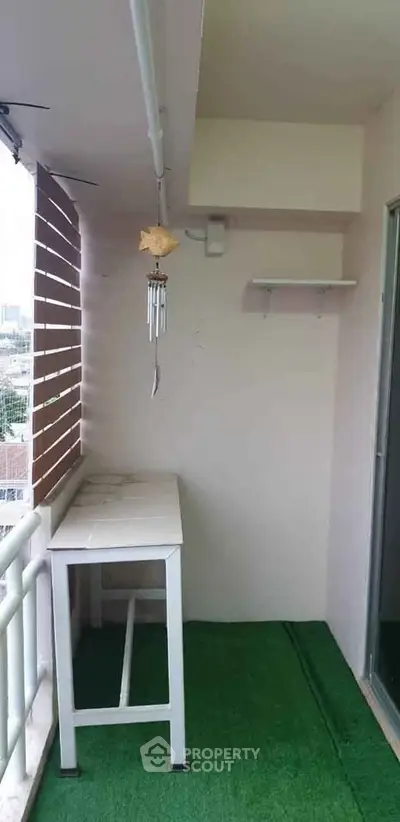 Charming balcony with green flooring and city view, perfect for relaxation and enjoying fresh air.