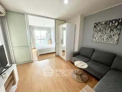 Modern living room with cozy gray sofa and stylish decor leading to a bright bedroom with balcony view.