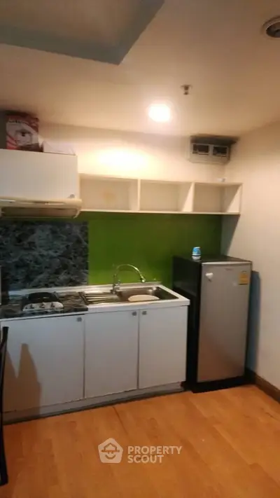 Compact kitchen with modern appliances and vibrant green backsplash