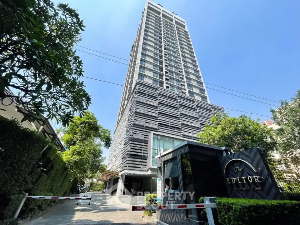 Modern high-rise condominium with lush greenery and secure entrance in prime location.
