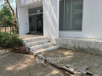 Modern building entrance with steps and garden, showcasing sleek architecture and outdoor design.