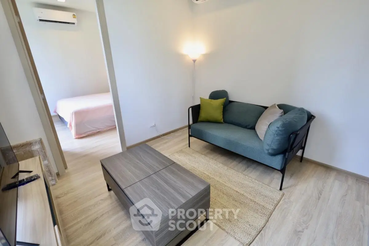 Modern living room with stylish furniture and natural light, leading to a cozy bedroom.
