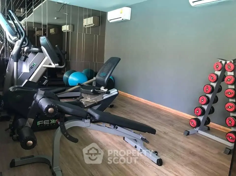 Modern gym with exercise equipment and weights in a stylish real estate property.