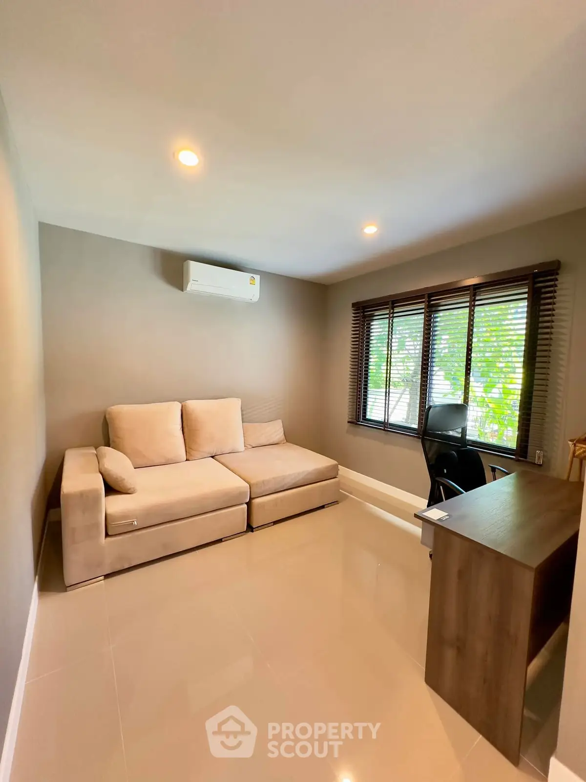 Modern study room with cozy sofa and desk, featuring large window and air conditioning.