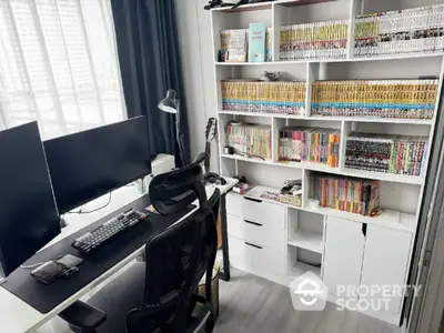 Modern study room with large desk, dual monitors, and extensive manga collection on shelves.