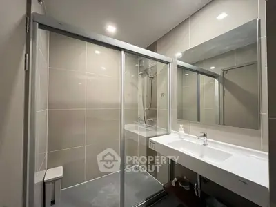 Modern bathroom with sleek shower and large mirror in contemporary apartment.