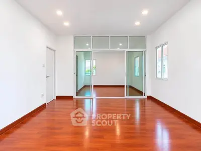 Spacious empty room with wooden flooring and sliding glass doors