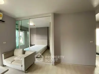 Modern bedroom with glass partition and cozy seating area in a stylish apartment.