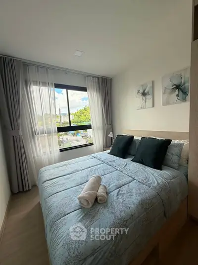 Cozy bedroom with large window and elegant decor, perfect for relaxation and comfort.