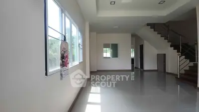 Spacious modern living room with large windows and staircase, perfect for family gatherings.