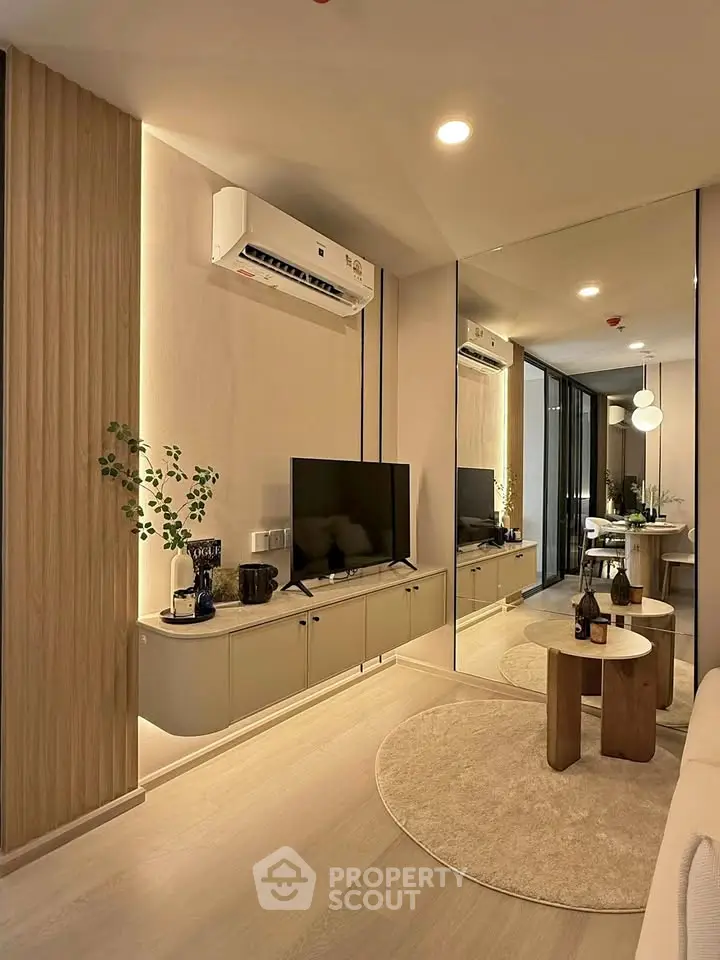Modern living room with sleek design and mirrored wall, featuring stylish furniture and ambient lighting.