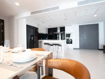 Modern open-layout kitchen with sleek black appliances and stylish dining area.