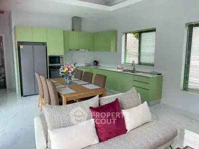 Modern kitchen with green cabinets and dining area in open layout design