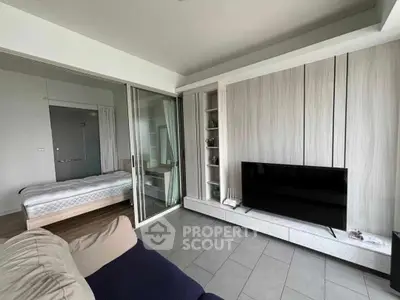 Modern living room with sliding glass doors to bedroom, featuring sleek TV setup and cozy seating.