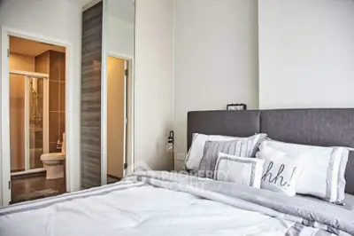 Modern bedroom with ensuite bathroom featuring stylish decor and cozy bedding.