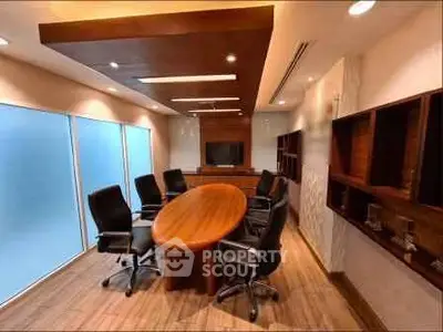 Modern conference room with wooden table and black chairs, ideal for meetings.