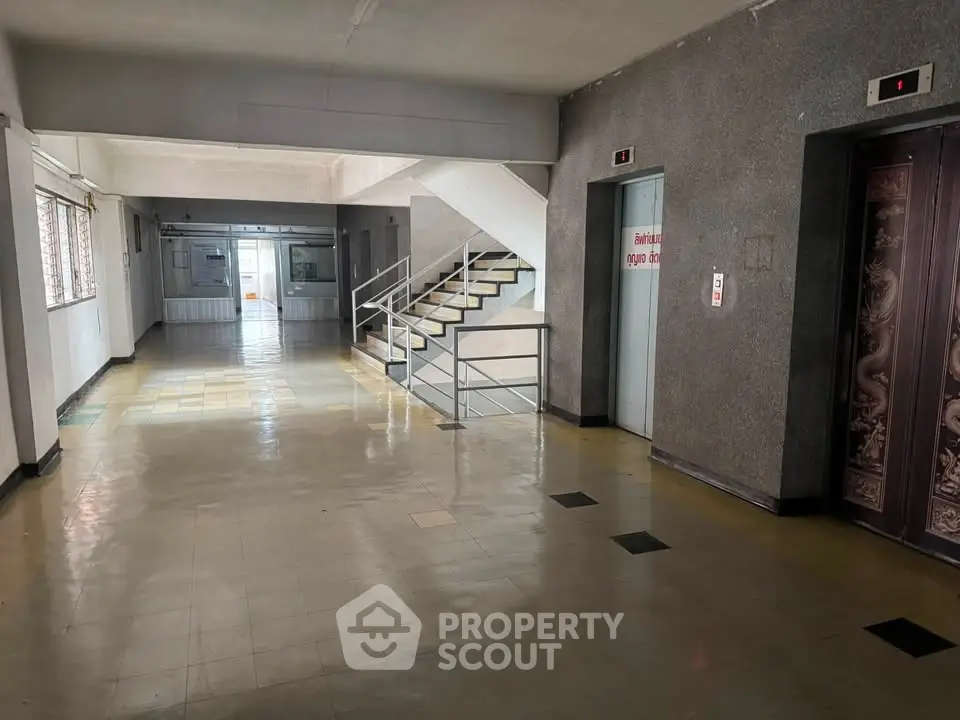 Spacious building corridor with elevators and stairway access, ideal for high-traffic areas.