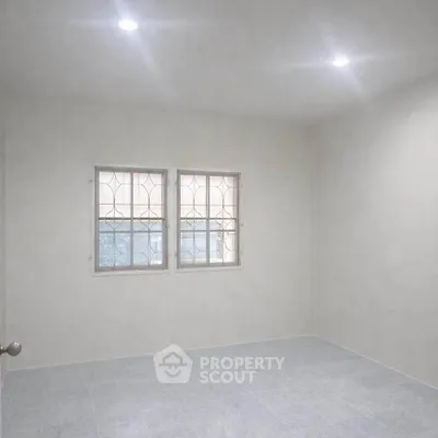 Spacious empty room with tiled floor and two windows, ideal for customization.