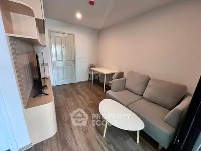Cozy living room with modern furniture and wooden flooring in a compact apartment.