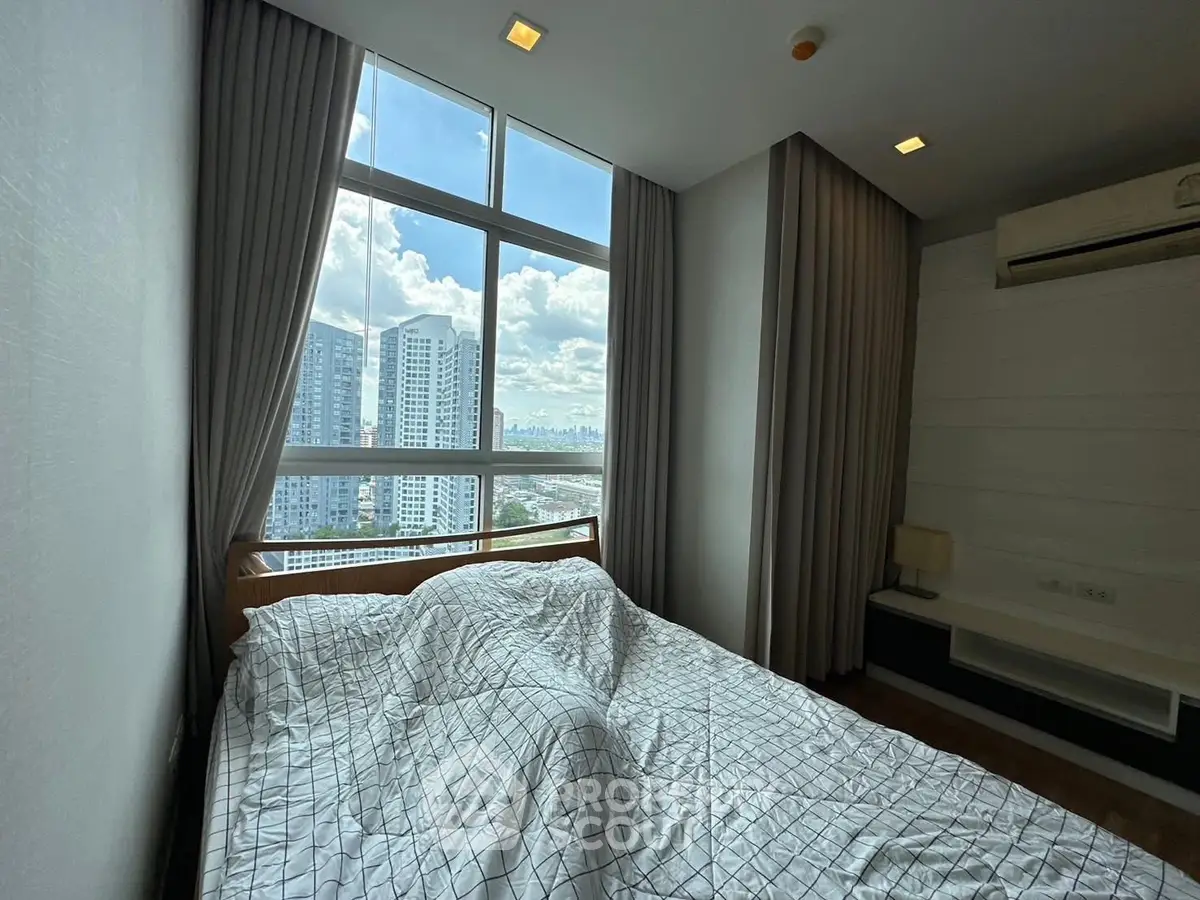 Modern bedroom with large window offering stunning city view, featuring cozy bed and elegant decor.
