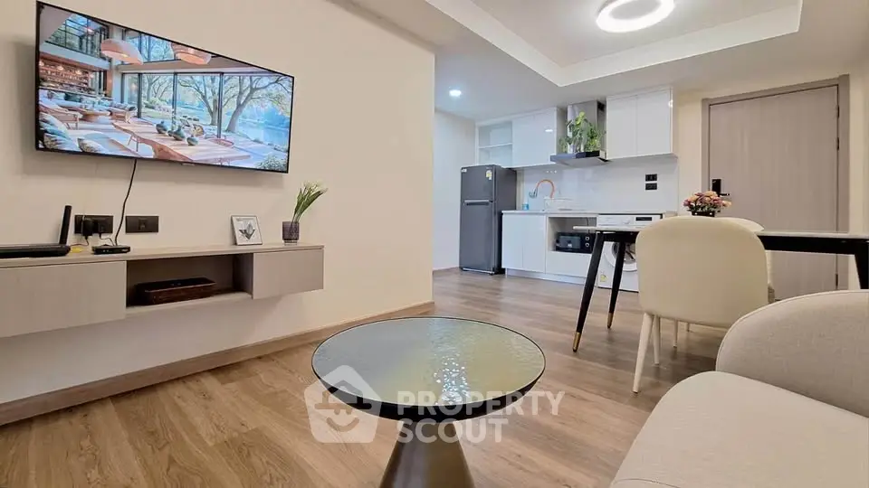 Modern open-plan living room with sleek kitchen, stylish furniture, and wall-mounted TV in a cozy apartment.