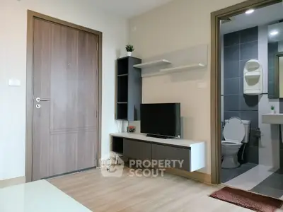 Modern living room with TV and bathroom view, featuring sleek design and wooden flooring.