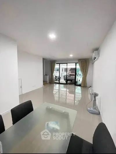 Spacious modern living room with glass table and large windows