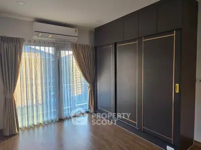 Modern bedroom with large wardrobe and natural light from balcony window.