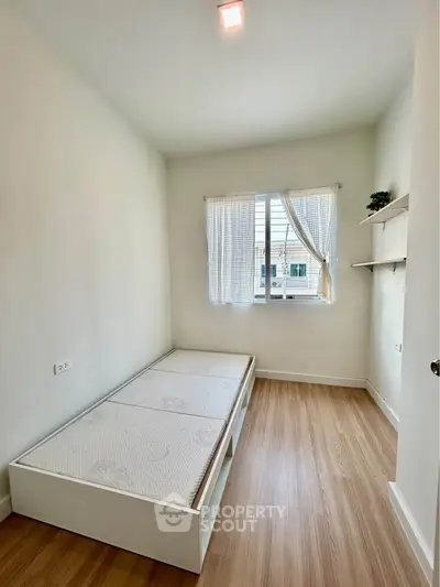 Bright minimalist bedroom with wooden flooring and large window