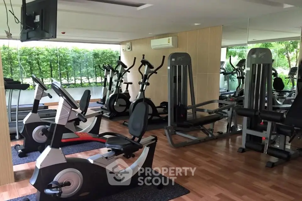 Modern gym with exercise equipment and mirrored walls in a residential complex.