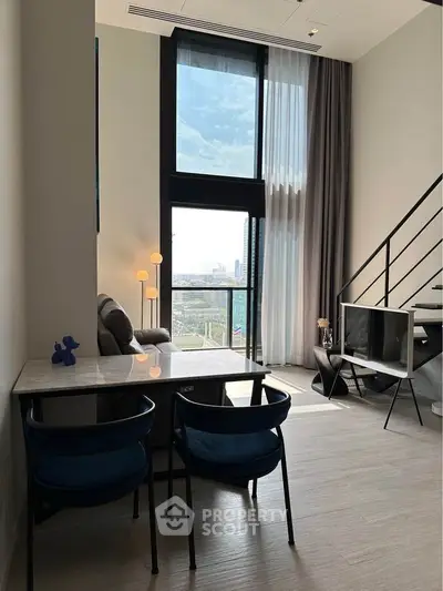 Modern loft apartment with large windows and stylish decor, featuring a cozy living area and city view.