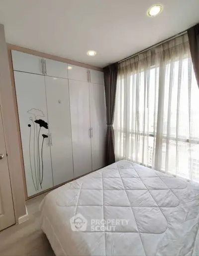 Bright bedroom with large window and stylish wardrobe in modern apartment