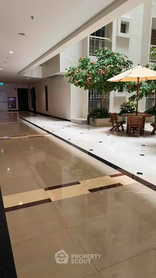 Elegant indoor common area with polished floors and seating under umbrellas, perfect for relaxation.