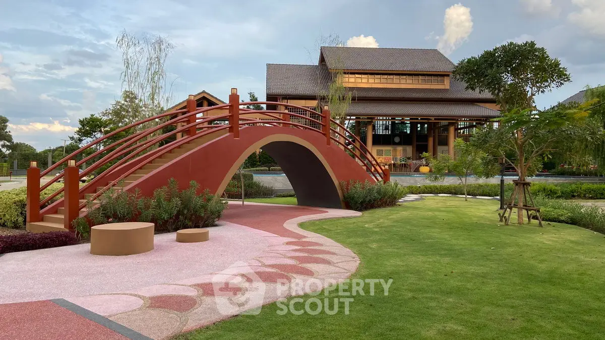 Charming garden with a picturesque bridge leading to a traditional-style house, perfect for serene living.