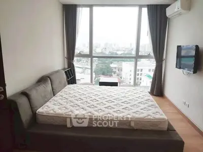 Spacious bedroom with large window and city view, featuring a comfortable bed and wall-mounted TV.