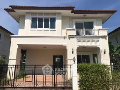 Charming two-story house with balcony and gated entrance in a serene neighborhood.