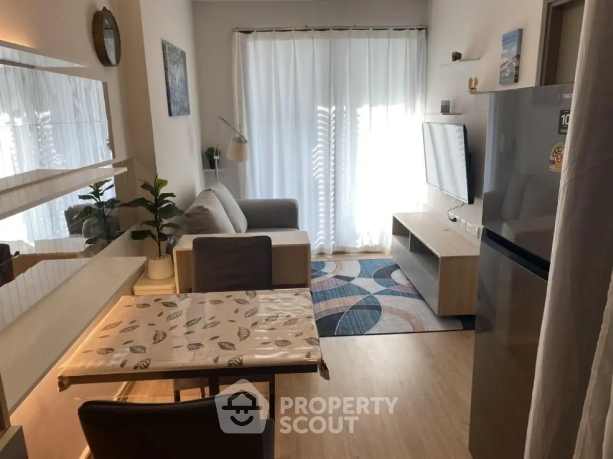 Modern living room with stylish decor and natural light, featuring a cozy sofa and sleek appliances.