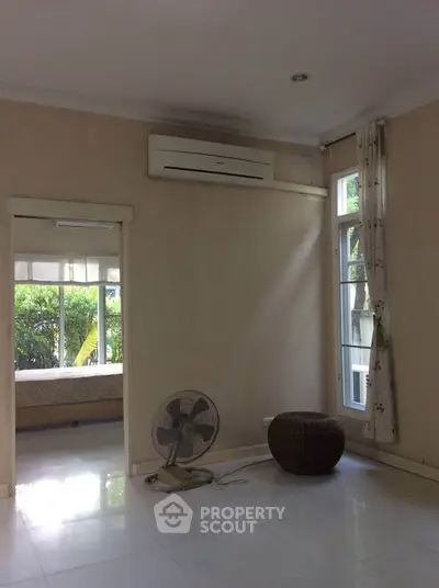 Spacious living room with air conditioning and large windows offering natural light.