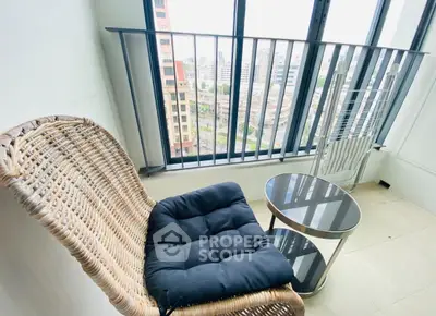 Charming balcony with city view, featuring cozy wicker chair and sleek glass table.